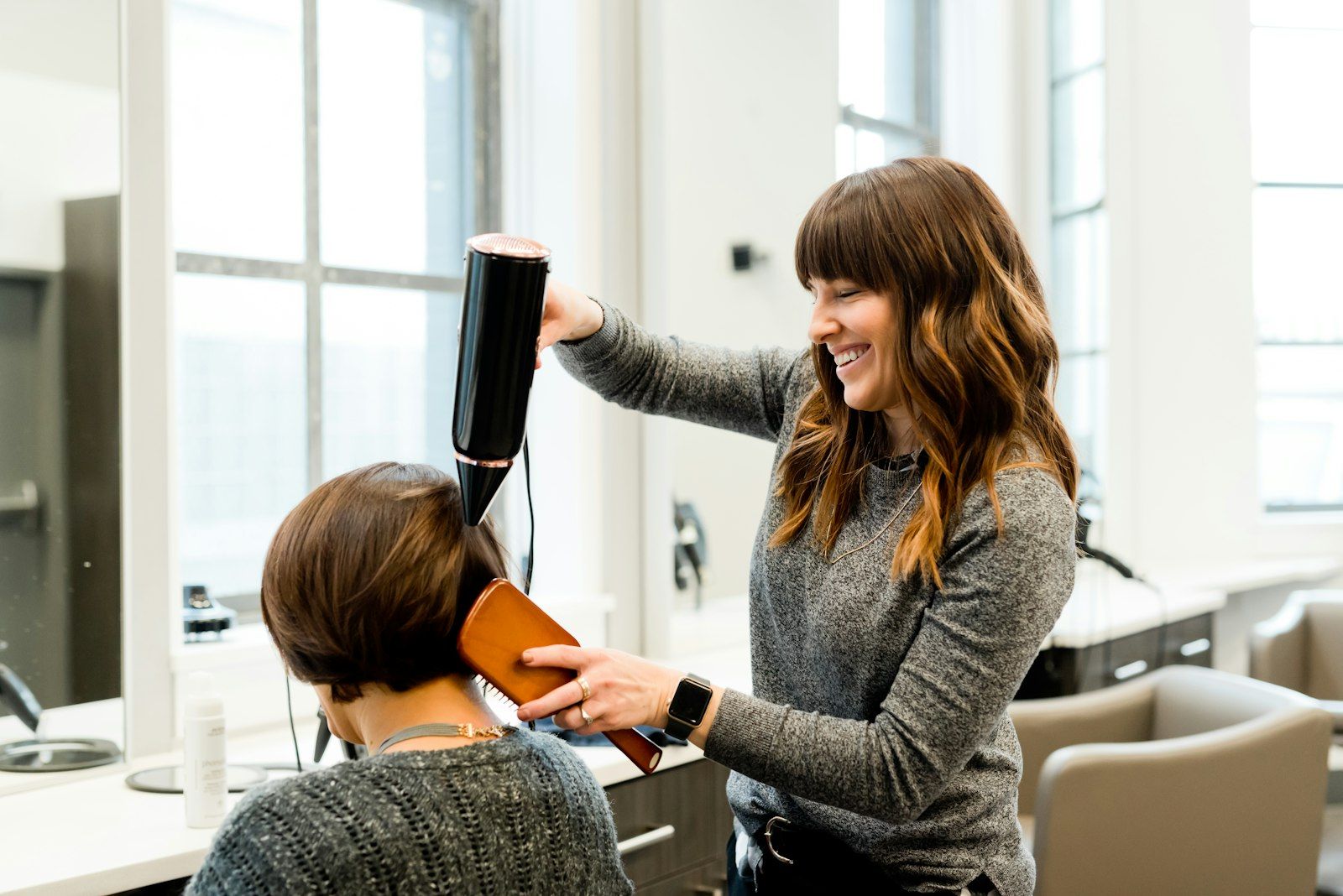 A stylist blow-drying a client’s hair