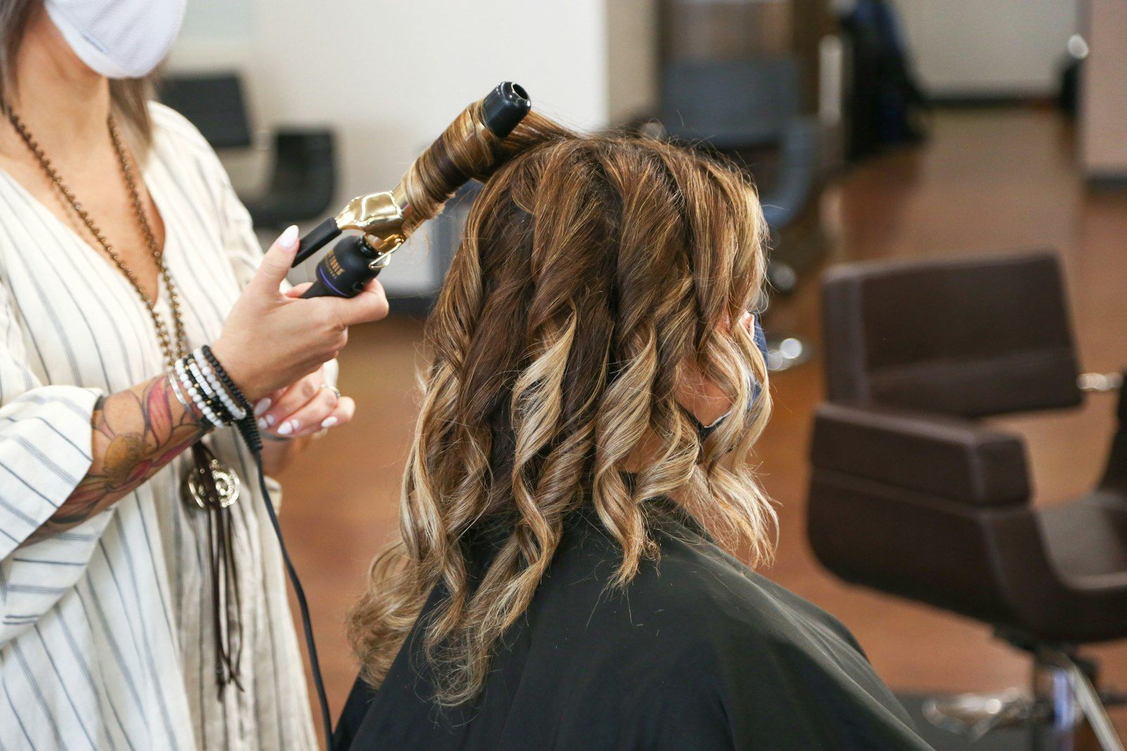 A stylist curling a client’s hair
