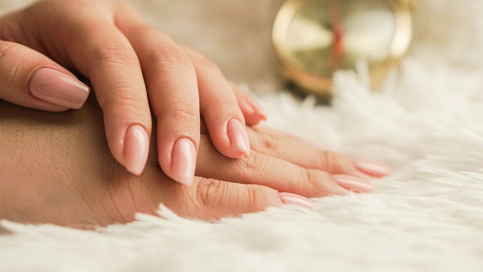 A soft nude manicure resting on white fur